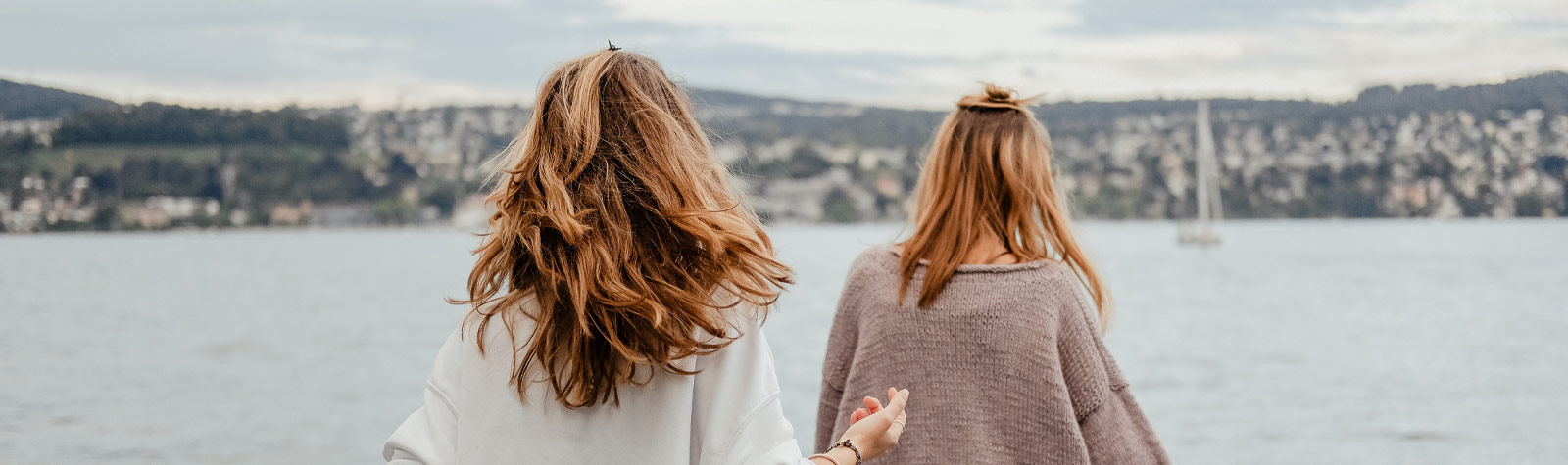 Zwei junge Frauen, die von hinten fotografiert wurden und in Richtung Hafengewässer schauen
