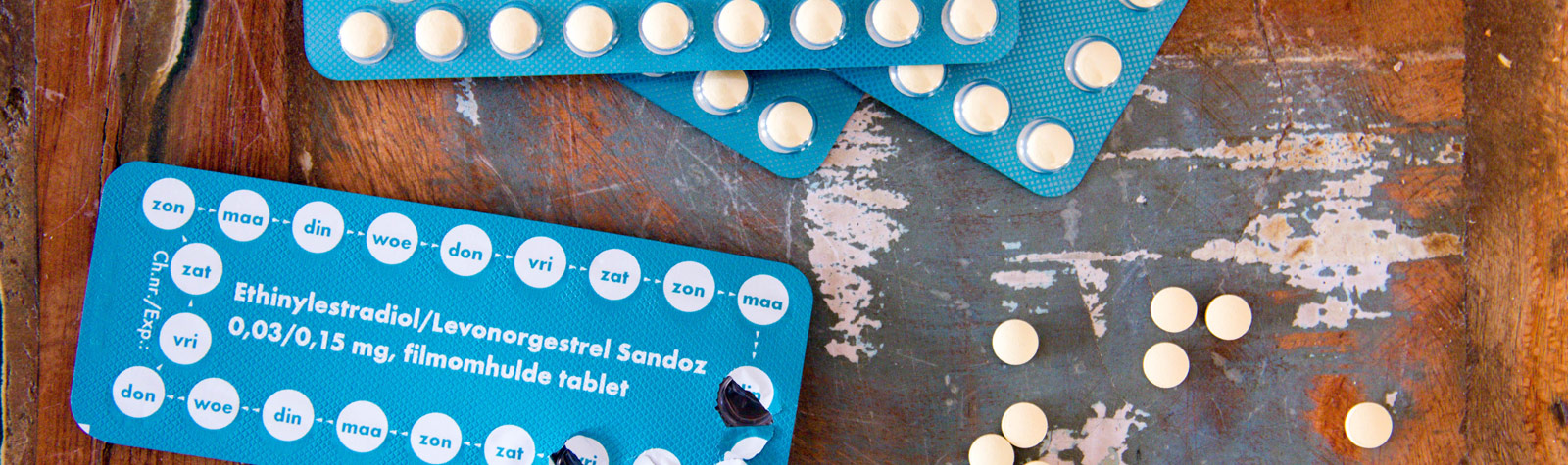mehrere blaue Blister mit der Anti-Baby-Pille auf hölzernem Untergrund